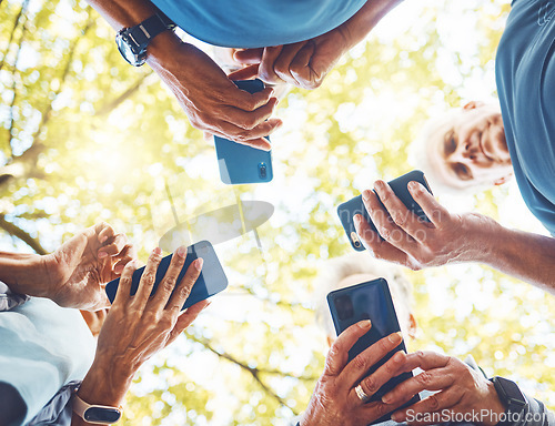 Image of Fitness, group with smartphone in hands and running in park, technology low angle and check exercise mobile app. Elderly runner team outdoor with health, phone for cardio and sports motivation.