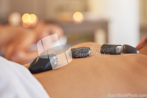 Image of Stone, man or woman at a spa for a massage, relaxing self care or luxury physical therapy healing for back pain. Hot stone massage, zoom or customer on a bed for healthy natural holistic treatment