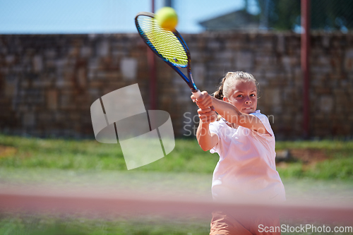 Image of A young girl showing professional tennis skills in a competitive match on a sunny day, surrounded by the modern aesthetics of a tennis court.