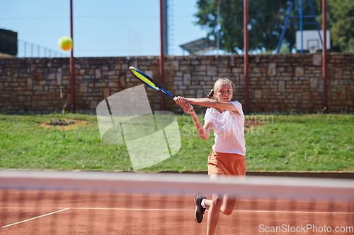 Image of A young girl showing professional tennis skills in a competitive match on a sunny day, surrounded by the modern aesthetics of a tennis court.