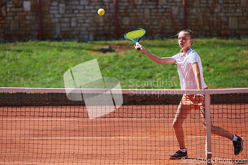 Image of A young girl showing professional tennis skills in a competitive match on a sunny day, surrounded by the modern aesthetics of a tennis court.