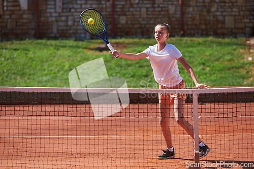 Image of A young girl showing professional tennis skills in a competitive match on a sunny day, surrounded by the modern aesthetics of a tennis court.