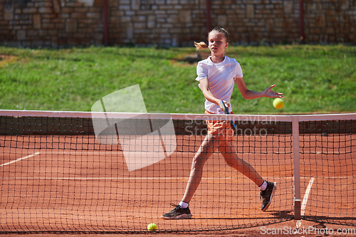 Image of A young girl showing professional tennis skills in a competitive match on a sunny day, surrounded by the modern aesthetics of a tennis court.