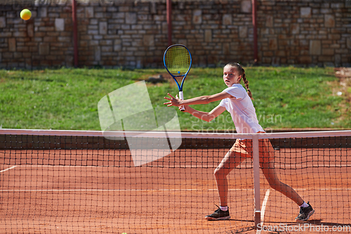 Image of A young girl showing professional tennis skills in a competitive match on a sunny day, surrounded by the modern aesthetics of a tennis court.