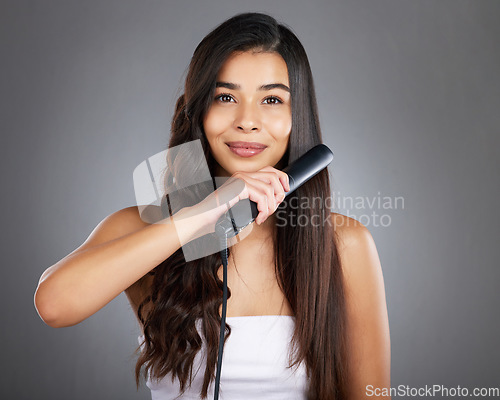 Image of Portrait, woman and hair straightener for care, natural beauty or treatment on grey studio background. Female, girl and salon equipment for luxury, ironing hair style and grooming routine for styling