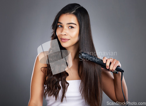 Image of Portrait, woman and hair straightener for care, natural beauty or treatment on grey studio background. Female, girl and salon equipment for luxury, ironing hair style and grooming routine for styling