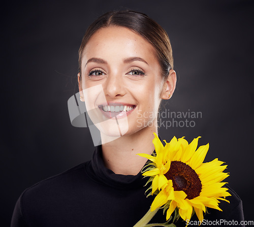 Image of Skincare, beauty and portrait of a woman with a sunflower in a studio for a clean, healthy and organic routine. Cosmetic, floral and model from Brazil with natural face treatment by black background.