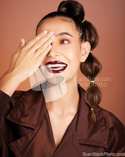 Image of Woman, beauty makeup and smile in studio with edgy fashion, hair and face by cosmetic background. Model, cosmetics and facial art with creative hairstyle, aesthetic and hand on eye by studio backdrop