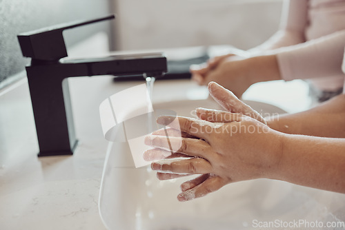 Image of Bathroom, water and children cleaning hands with soap, foam or learning healthy hygiene together. Washing dirt, germs or bacteria on fingers, kids in home in morning for wellness, safety or skin care