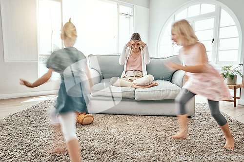 Image of Mother, children and running in living room chaos with headache in stress on sofa at crazy or busy home. Frustrated single parent in burnout with ADHD or hyperactive kids or siblings playing in house