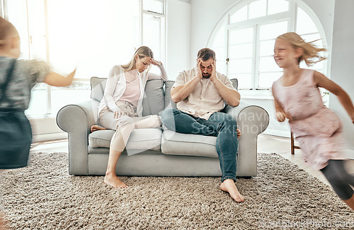 Image of Frustrated couple, children and running in living room chaos with headache in stress on sofa at crazy or busy home. Parents in burnout with ADHD or hyper active kids or siblings playing wild in house