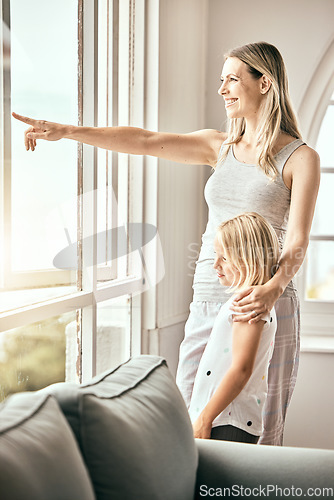 Image of Window, pointing and mother with girl in home looking outdoors for bonding, relationship and relax. Happy family, house and mom with child in living room for scenic view on weekend, morning and fun