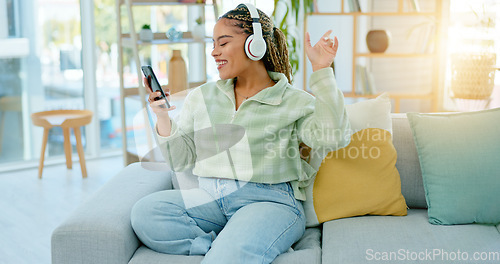 Image of Phone, sofa and happy woman on music headphones in home living room for dancing. Mobile, radio and African person listening to podcast, audio and sound for freedom, celebration and streaming online