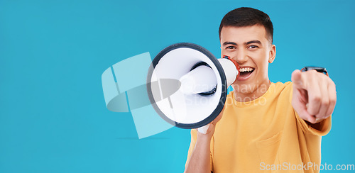 Image of Megaphone, smile and portrait of man in studio pointing for announcement, speech or rally. Happy, protest and young person from Canada with bullhorn for loud communication isolated by blue background