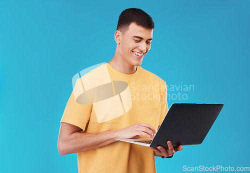 Image of Laptop, research and man student in a studio working on a university project on the internet. Smile, technology and young male person studying for college test or exam on computer by blue background.