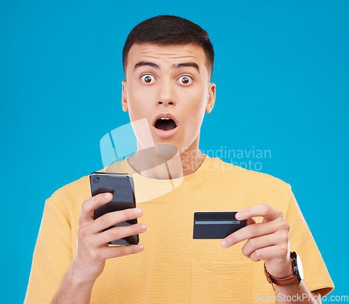 Image of Credit card, ecommerce and man with a cellphone, surprise and transaction on a blue studio background. Person, shock and model with a smartphone, digital app and online banking with finance and fraud