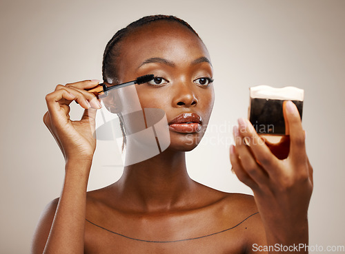 Image of Black woman, mascara with brush and mirror for beauty, makeup and shine isolated on brown background. Eyelash extension, wand and skin glow with cosmetology, transformation and wellness in studio