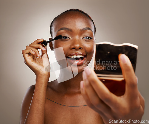 Image of Black woman, mascara with brush and mirror, makeup and shine with beauty isolated on brown background. Eyelash extension, wand and skin glow with cosmetology, transformation and wellness in studio