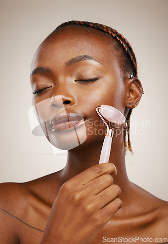 Image of Woman, hand and roller for face on studio background for beauty, skincare or cosmetics. Female model, relaxed and massage with facial, wellness and tool for lymphatic drainage, anti aging or glow