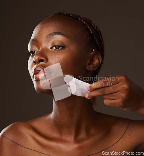 Image of Woman, facial and gua sha in hand on studio background for mockup in beauty, treatment or skincare. Black person, model or massage for glow, lymphatic drainage or grooming with tool, relax and shine