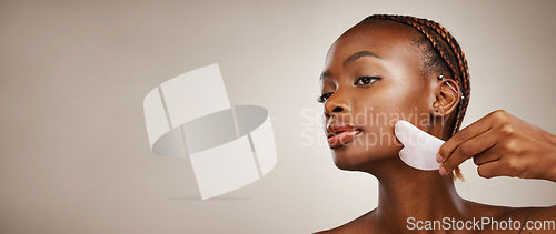 Image of Skincare, black woman or gua sha on face for beauty, acne or blood circulation in studio on brown background. Cosmetic, person and facial product for lymphatic drainage, wellness and mock up for skin
