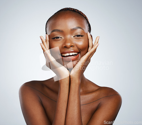 Image of Portrait, beauty and hands on the cheek of a black woman in studio on a gray background for skincare or natural wellness. Smile, spa or luxury and a young model with cosmetic or antiaging treatment