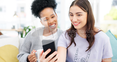 Image of Coffee, cellphone and girl friends on sofa talking, bonding and networking on social media or mobile app. Happy, conversation and young women scroll on a phone with latte in living room of apartment.