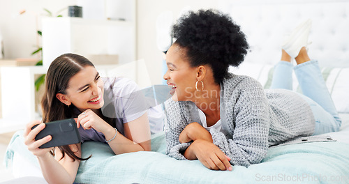 Image of Phone, social media and woman friends laughing on bed together while looking at an internet meme. Smile, diversity and comedy with funny young people joking in the bedroom of a home in the morning