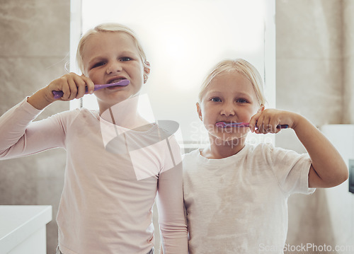 Image of Children, brushing teeth and a girl with her sister in the bathroom of their home together for oral hygiene. Portrait, dental cleaning and siblings using a toothbrush in the morning for mouth care