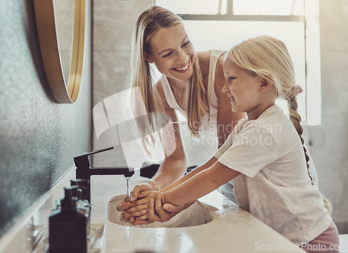 Image of Bathroom, mother and child washing hands with water, soap and learning healthy hygiene together. Cleaning dirt, germs or bacteria on fingers, mom and girl in home for morning wellness, help and care.