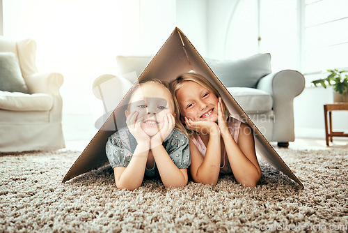 Image of Portrait, children and cardboard for insurance with girl sisters on the floor of the living room at home. Security. family or kids and young siblings on a carpet in their house for safety with flare