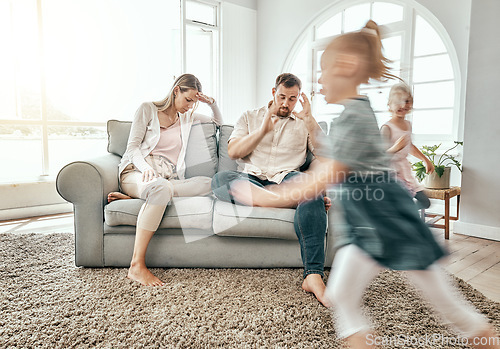 Image of Family, adhd children and parents headache, stress and anxiety for autism management, energy fatigue or home noise. Tired mother and father on sofa with chaos and hyper or fast, excited kids running