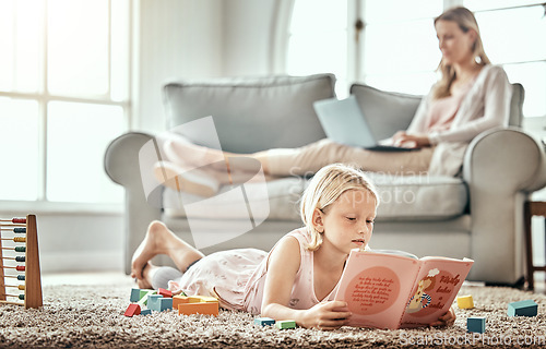 Image of Child, floor and reading book for learning, language development and mother work from home in living room. Girl or kid with English story, education and relax on carpet with mom or family on sofa