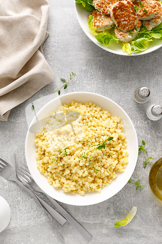 Image of Couscous with chicken patties, cutlets with fresh romaine lettuce salad, top down view