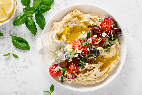 Image of Greek style vegan mediterranean hummus with fresh vegetables, olives, olive oil and feta cheese. Top view