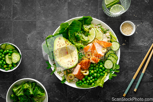 Image of Salmon avocado bowl with broccoli, green peas, rice and fresh salad. Healthy food, top view