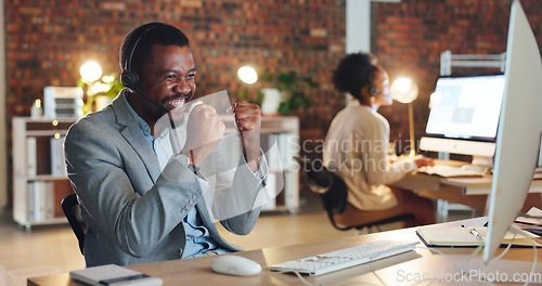 Image of African man, call center and celebration by computer, smile and excited for promotion, goals or success. Consultant, winner or agent in night, telemarketing or customer service with fist in workplace