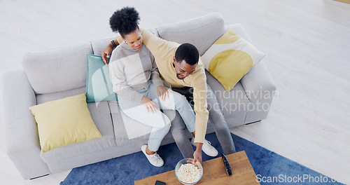 Image of Couple, watching tv and eating popcorn in home, living room and date in apartment with comedy or movies. Happy, people and together on sofa with food to watch tv show or film or above lounge in house