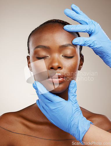 Image of Portrait, gloves and plastic surgery on face of a black woman in studio on a gray background for cosmetic change. Patient, skincare transformation and a young model getting ready for facial treatment