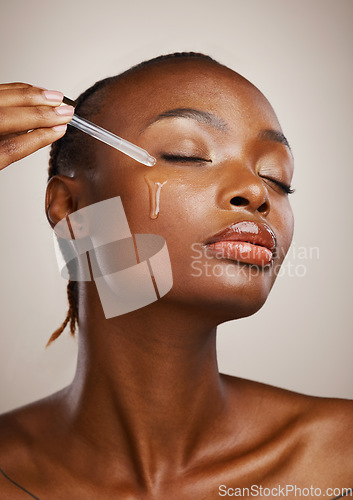 Image of Woman, skincare and oil on face in studio for beauty, dermatology and collagen product on brown background. African model, facial cosmetics and dropper of hyaluronic acid, liquid and serum for shine