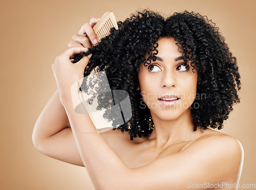 Image of Afro, brush and hair of woman in studio for beauty, natural growth and grooming on brown background. Model comb curly hairstyle, coil texture and care for salon aesthetic, healthy treatment and shine
