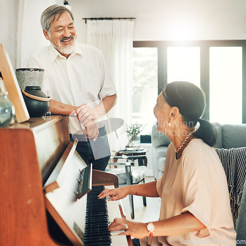 Image of Elderly couple playing piano for music in living room for bonding, entertainment or having fun. Happy, smile and senior Asian man and woman in retirement enjoying keyboard instrument at modern home.