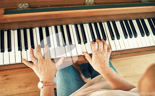 Image of Hands, piano and senior woman playing for music in living room for musical entertainment practice. Instrument, hobby and elderly female person in retirement enjoying a song on keyboard at modern home