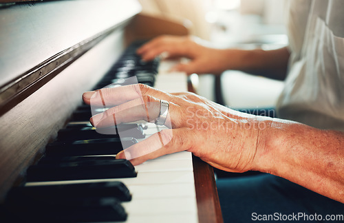 Image of Hands, piano and senior man playing for music in living room for musical entertainment practice. Instrument, hobby and elderly male person in retirement enjoying a song on keyboard at modern home.