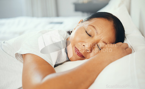 Image of Mature, woman and calm while sleeping in bed with good dream, head on pillow and peace. Asian, elderly person and face in bedroom, alone and smile with happiness while rest with retirement in home