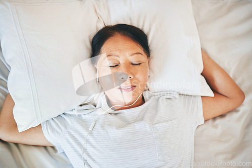 Image of Bedroom face, music and relax woman sleeping, tired or nap for break, morning wellness or listening to audio podcast. Fatigue, radio sound and top view person cozy, dream and exhausted on home bed