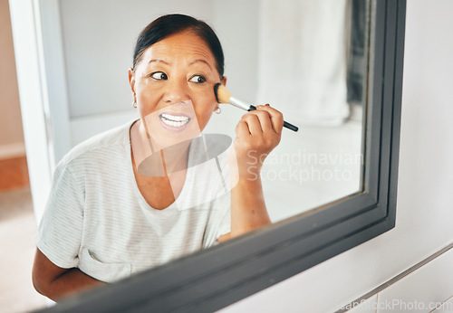 Image of Woman, mirror and brush makeup in home for foundation, cheek contour and grooming routine. Face, mature asian person and facial beauty powder for skincare, aesthetics or cosmetics tools in reflection