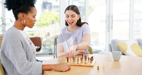 Image of Girl friends playing chess in the living room for bonding, entertainment or having fun together. Happy, smile and young interracial women enjoying board game in the lounge of modern apartment.
