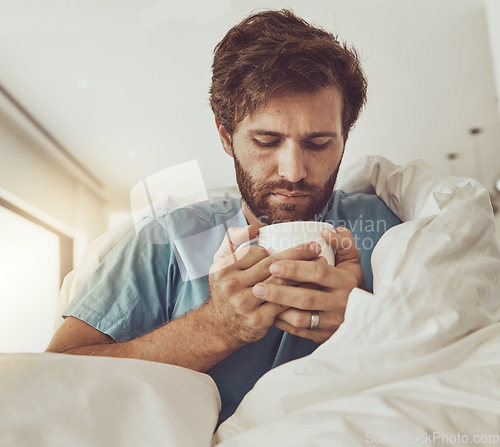 Image of Tea, sick and a man with a blanket on a sofa in the living room of his home for recovery from cold or flu. Coffee, healthcare or lemon and ginger drink in a cup with a young person feeling unwell