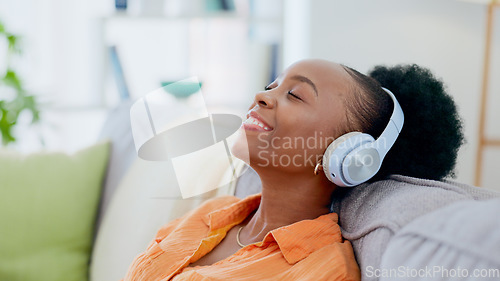 Image of Calm woman, music and headphones in home for listening to audio, radio and hearing podcast on sofa. Happy african person relax for streaming sound, multimedia and peaceful subscription in living room